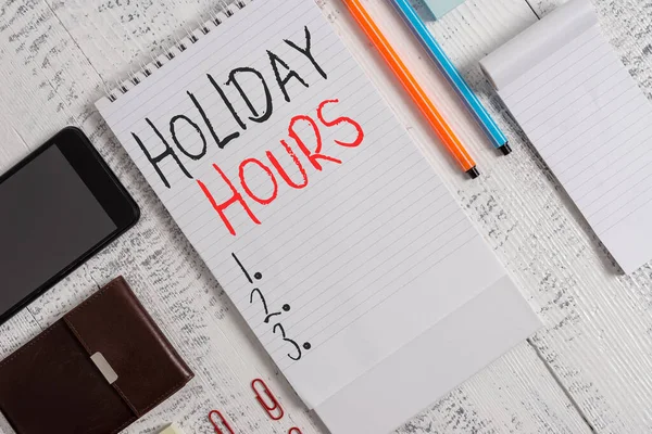 Käsiala teksti Holiday Hours. Käsitteen merkitys työntekijä saa kaksinkertaisen normaalin palkan kaikkina tunteina Älypuhelin mies lompakko leikkeet muistikirja kynät kuulakärkikynät muistilehtiö puinen pöytä . — kuvapankkivalokuva