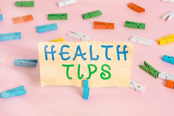 Text sign showing Health Tips. Conceptual photo advice or information given to be helpful in being healthy Colored clothespin papers empty reminder pink floor background office pin.