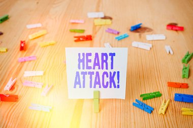 Kalp krizini gösteren bir not yazıyorum. Ölümle sonuçlanan koroner trombozun aniden ortaya çıkan iş fotoğrafı. Renkli çamaşır iğnesi kağıtları boş ahşap zemin ofisini hatırlatıyor..