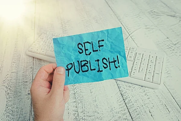 Слово, що пише текст Self Publish. Бізнес-концепція для письменника публікувати шматок з них працює самостійно за свій рахунок людина тримає барвисте нагадування квадратної форми паперу біла клавіатура дерев'яна підлога . — стокове фото