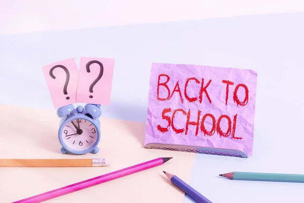 Signo de texto que muestra Volver a la escuela. Foto conceptual es el período relacionado con el inicio de un nuevo año escolar Mini reloj despertador de tamaño junto a estacionario colocado inclinado sobre fondo pastel . —  Fotos de Stock