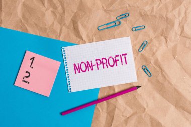 Non Profit 'i gösteren mesaj işareti. Sahiplerine Papercraft kağıt masa karesi sarmal defter ofis malzemeleri için kâr etmeyen kavramsal fotoğraf tipi bir organizasyon..