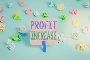 Profit Increase 'i gösteren kavramsal el yazısı. İş fotoğrafı, bir işten elde edilen gelir miktarını gösteriyor. Renkli buruşuk kağıtlar boş mavi zemin mandalını hatırlatıyor..