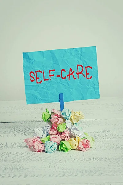 Conceptual hand writing showing Self Care. Business photo showcasing the practice of taking action to improve one own health Reminder pile colored crumpled paper clothespin wooden space. — Stock Photo, Image