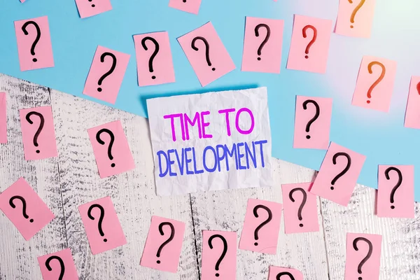 Handwriting text writing Time To Development. Concept meaning a length of time during which a company grows or develop Scribbled and crumbling papers with thick cardboard above wooden table.