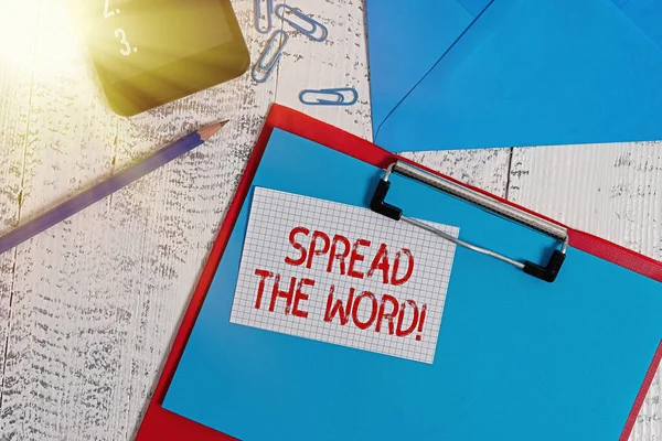 「 Spread The Word 」を示すテキスト記号。概念的な写真は、ソーシャルメディアを使用して情報やニュースを共有するクリップボードシート鉛筆ノートクリップスマートフォンの封筒木製の背景. — ストック写真