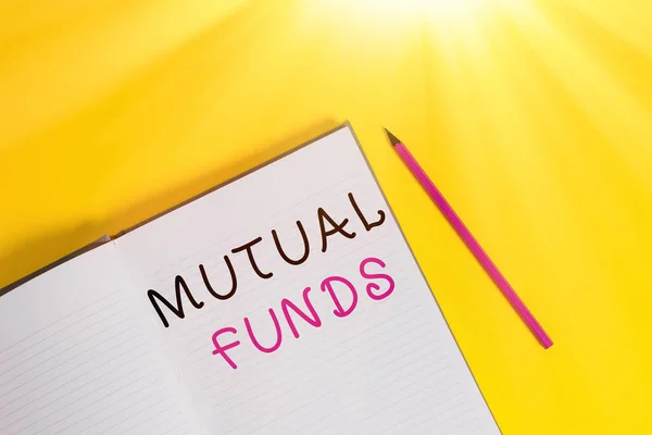 Text sign showing Mutual Funds. Conceptual photo collection of stocks bonds or other securities from investors Open striped hard cover notebook lying pencil marker color background.