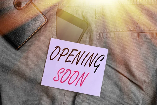 Writing note showing Opening Soon. Business photo showcasing an act or instance of making or becoming open to the public Smartphone device inside trousers front pocket with wallet.
