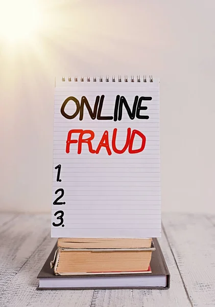 Conceptual hand writing showing Online Fraud. Business photo text use of Internet services to deceive victims and steal money Front view stacked books spiral note book on vintage wooden table.