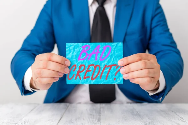 Handwriting text Bad Creditquestion. Concept meaning inability to repay a debt on time and in full Man holds empty paper with copy space in front of him Copy Space.