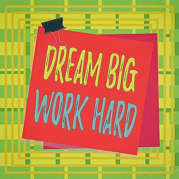 Text sign showing Dream Big Work Hard. Conceptual photo Believe in yourself and follow the dreams and goals Paper stuck binder clip colorful background reminder memo office supply.