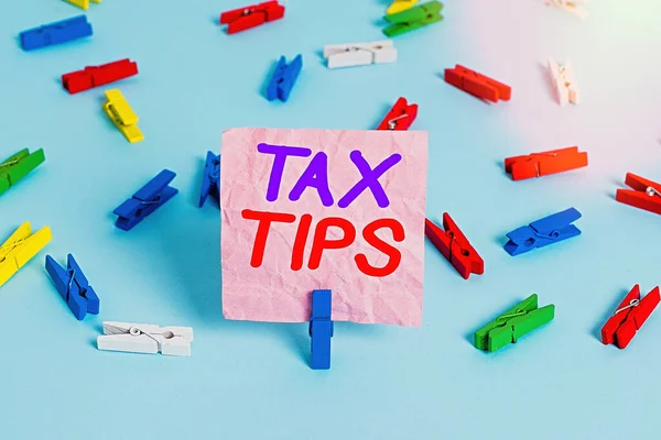 Handwriting text Tax Tips. Concept meaning compulsory contribution to state revenue levied by government Colored clothespin papers empty reminder blue floor background office pin.
