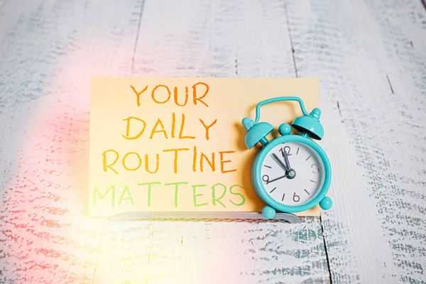 Word writing text Your Daily Routine Matters. Business concept for practice of regularly doing things in fixed order Mini blue alarm clock stand tilted above buffer wire in front of notepaper. — Stock Photo, Image