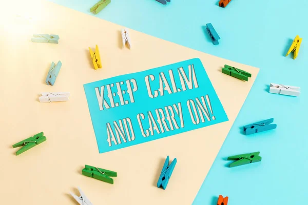 Schreiben Notiz zeigt Keep Calm And Carry On. Business-Foto mit Slogan Aufruf zur Beharrlichkeit Gesicht der Herausforderung Farbige Wäscheklammer Papier Erinnerung mit gelb-blauem Hintergrund. — Stockfoto