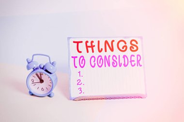 Düşünecek Şeyler 'i gösteren bir not yazıyorum. İş fotoğraflarının sergilenmesi özellikle karar verirken Pastel arkaplana yerleştirilmiş bir kağıdın yanında alarm saatini iyi düşünün..