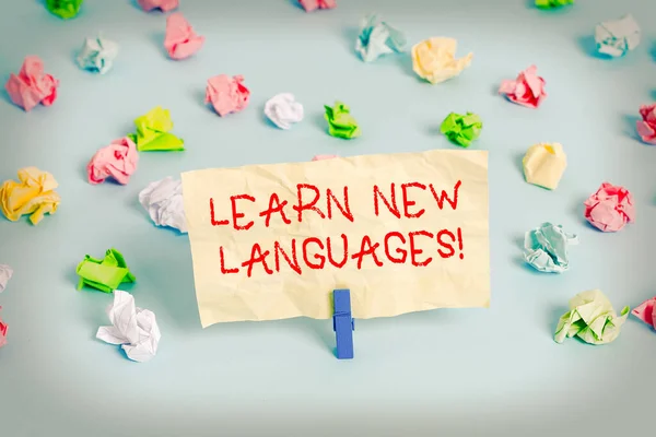 単語の書き方新しい言語を学びます。外国語でコミュニケーション能力を開発するためのビジネスコンセプト色の砕いた紙空のリマインダ青の床の背景の服ピン. — ストック写真