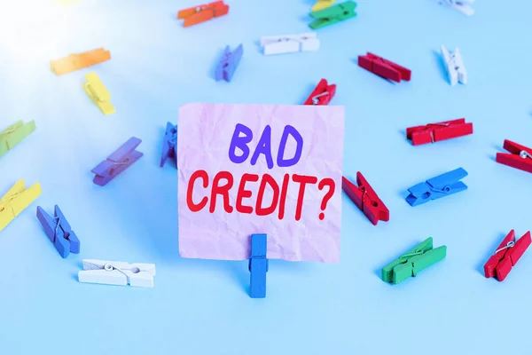 Handwriting text Bad Creditquestion. Concept meaning inabilityof a demonstrating to repay a debt on time and in full Colored clothespin papers empty reminder blue floor background office pin.