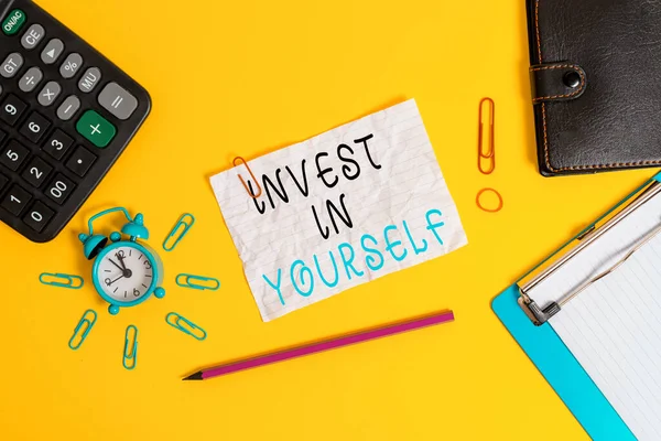 Escrevendo nota mostrando Invest In Yourself. Foto de negócios mostrando a colheita em um treinador ou um treinamento para aprender coisas novas Alarme relógio prancheta calculadora carteira clipe banda lápis esmagado folha . — Fotografia de Stock