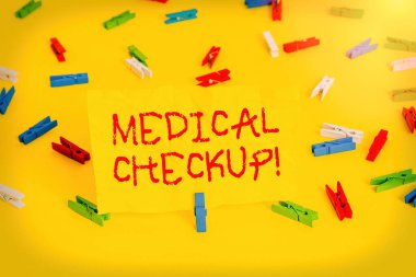 El yazısı, tıbbi kontrol metni. Ayrıntılı fiziksel muayene anlamına gelen kavram çeşitli testler içerir Renkli çamaşır iğnesi kağıtları boş hatırlatıcı sarı zemin arka plan ofisi.