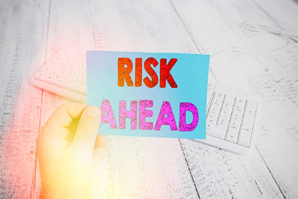 Handwriting text writing Risk Ahead. Concept meaning A probability or threat of damage, injury, liability, loss man holding colorful reminder square shaped paper white keyboard wood floor. — Stock Photo, Image