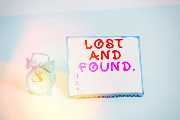 Writing note showing Lost And Found. Business photo showcasing a place where lost items are stored until they reclaimed Alarm clock beside a Paper sheet placed on pastel backdrop. — Stock Photo, Image