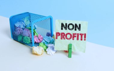 Non Profit 'i gösteren bir not yazıyorum. Sahiplerine kâr sağlamayan iş fotoğrafçılığı türü bir organizasyon. Çöp tenekesi buruşmuş kağıt çamaşır mandalı ofis malzemeleri..