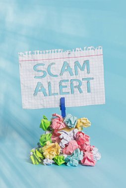 Kelime yazma dolandırıcılığı alarmı. İş konsepti, birini entrika ya da dolandırıcılık hakkında uyarmak için dikkat edilmesi gereken sıra dışı hatırlatıcı yığın renginde buruşmuş kağıt çamaşır mandalı mavi arkaplan.