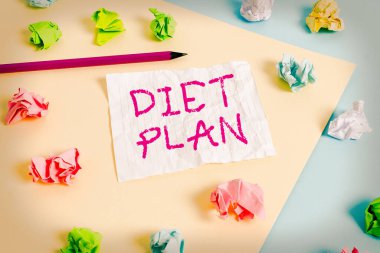 Diyet Planı 'nı gösteren metin işareti. Sağlıklı beslenme alışkanlığı yapmak ya da elde etmek için kavramsal fotoğraf detaylı önerisi. Renkli buruşuk kağıtlar boş mavi arka plan çamaşır mandalı..
