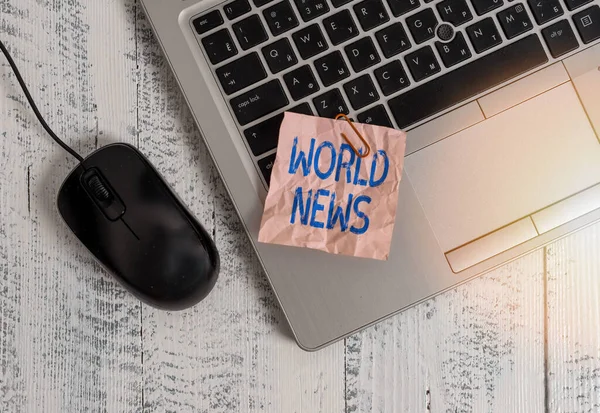 Writing note showing World News. Business photo showcasing global noteworthy information about recent or important events Trendy metallic laptop crushed colored paper note pen on wooden table.