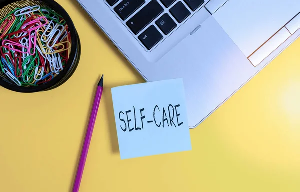 Handwriting text writing Self Care. Concept meaning the practice of taking action to improve one s is own health Metallic laptop sticky note clips container pencil colored background. — Stock Photo, Image