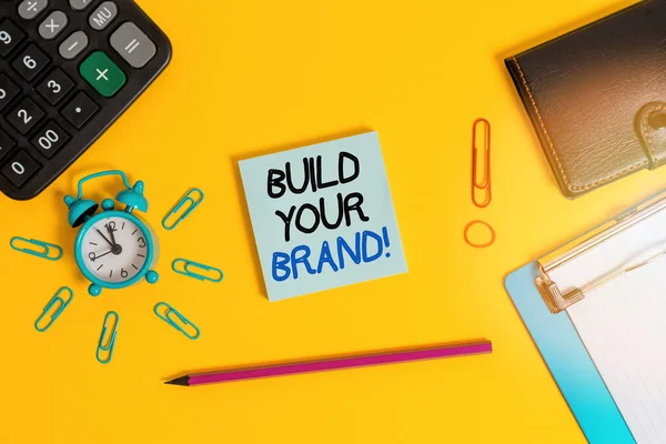 브랜드 구축을 보여 주는 문자 표지판. 컨셉 포토는 제품에 대한 고객의 지식 과 의견을 만들어 내거나 개선 합니다 . Alarm clipboard 계산기 지갑 클립 연필 메모지 색 배경. — 스톡 사진