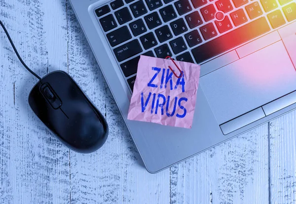 Writing note showing Zika Virus. Business photo showcasing caused by a virus transmitted primarily by Aedes mosquitoes Trendy metallic laptop crushed colored paper note pen on wooden table.