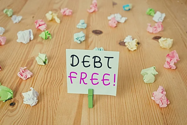 Handwriting text Debt Free. Concept meaning free from owning any money to any individual or a company Colored crumpled papers empty reminder wooden floor background clothespin.