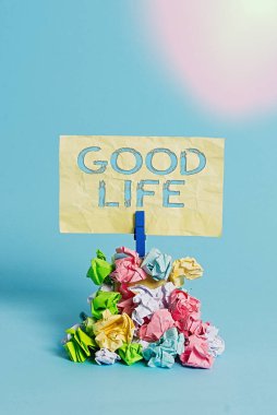 İyi Hayat 'ı yazan el yazısı. Konfor ve lüks içinde yaşamanın konsepti, birkaç sorun ve endişeyle. Renkli, buruşuk kağıt çamaşır mandalı, mavi arka planı hatırlatır..