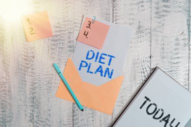 Diyet Planı 'nı gösteren bir not yazıyorum. Sağlıklı beslenme alışkanlığı edinmek ya da elde etmek için ayrıntılı bir teklif sunan iş fotoğrafı kağıdı yapışkan kağıt kalem not defteri ahşap arkaplan.
