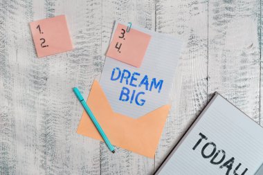 Dream Big 'i gösteren bir not yazıyorum. Hayatınız için amaç arayışında olan iş fotoğrafı gösterimi ve süreç içinde tamamlanma kağıt yapışkan notlar kalem not defteri tahta arkaplan.