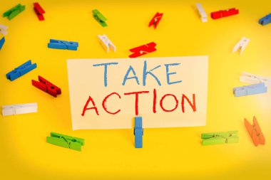 Kelime yazma metni Harekete Geç. İş konsepti belirli bir sonuç elde etmek için bir şeyler yapmak için Renkli çamaşır iğnesi kağıtları boş hatırlatıcı sarı zemin arka plan ofisi.