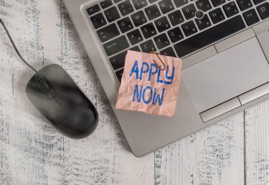 Şimdi Uygula 'yı gösteren not yazıyorum. İş fotoğrafı gösterimi mesleğiyle ilgili bir gösteri. Metalik dizüstü bilgisayar. Ahşap masa üzerinde renkli kağıt kalem..