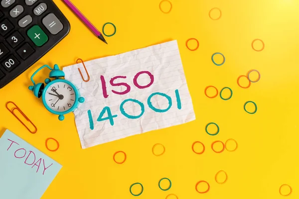 Konzeptionelle Handschrift, die Iso 14001 zeigt. Business-Foto-Text einer Familie von Standards im Zusammenhang mit Umweltmanagement Wecker beachten Gummibänder Taschenrechner Bleistift farbigen Hintergrund. — Stockfoto