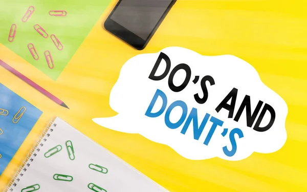 Conceptual hand writing showing Do S And Dont S. Business photo showcasing Rules or customs concerning some activity or actions Sheets message pencil smartphone plain colored background.