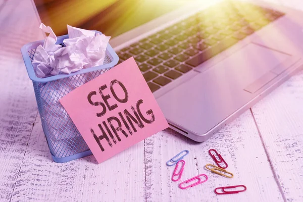 Conceptual hand writing showing Seo Hiring. Business photo showcasing employing a specialist will develop content to include keywords Metallic laptop sticky note bin paper clips vintage table.