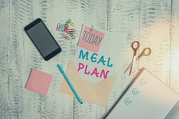 Tekstbord met Meal Plan. Conceptuele foto arrangement schema van wat er gaat eten volgende week maand Envelop blad smartphone notities pen notitieblok clips schaar houten rug. — Stockfoto