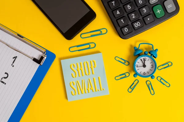 Word writing text Shop Small. Business concept for nationwide movement that celebrates small businesses every day Alarm clock clipboard clips smartphone calculator notepad color background.