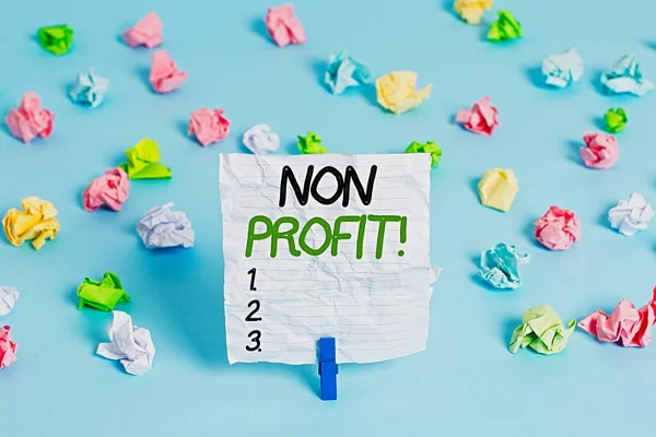 Non Profit 'i gösteren mesaj işareti. Sahiplerine kar getirmeyen kavramsal fotoğraf tipi bir organizasyon. Kırışmış renkli kağıtlar. Boş hatırlatıcı mavi zemin çamaşır mandalı..
