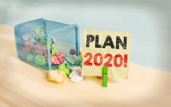 Writing note showing Plan 2020. Business photo showcasing detailed proposal doing achieving something next year Trash bin crumpled paper clothespin reminder office supplies.