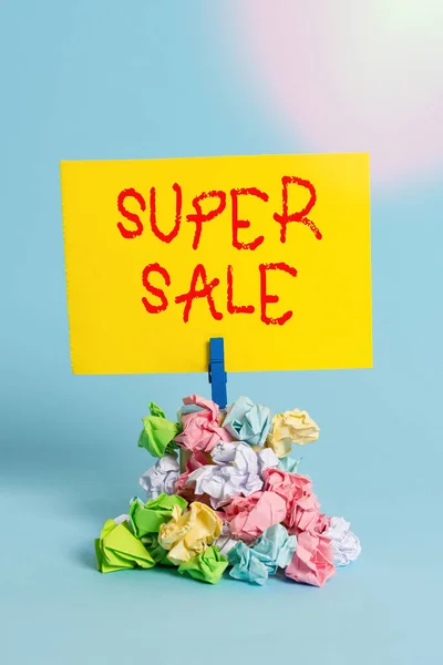 Текст для написания слов Super Sale. Бизнес-концепция для предоставления исключительных скидок на выбранные продукты и услуги Напоминаем кучи цветной скомканной бумаги, прищепки напоминают синий фон . — стоковое фото