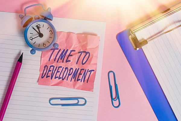 Text sign showing Time To Development. Conceptual photo a length of time during which a company grows or develop Paper sheet note clipboard pencil clips alarm clock colored background.