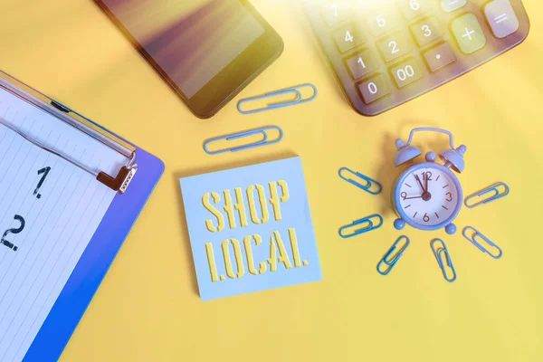 Word writing text Shop Local. Business concept for a preference to buy locally produced goods and services Alarm clock clipboard clips smartphone calculator notepad color background.