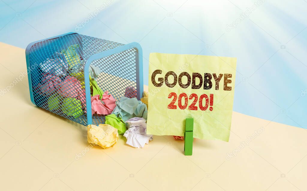 Writing note showing Good Bye 2020. Business photo showcasing express good wishes when parting or at the end of last year Trash bin crumpled paper clothespin reminder office supplies.