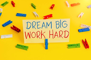 Kelime yazma metni Dream Big Work Hard. Kendine inan ve hayallerini ve hedeflerini takip et. Renkli çamaşır mandalı kağıtları boş hatırlatıcı sarı zemin ofis..